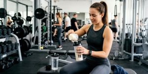 Jeune femme à la salle de sport prend de la whey